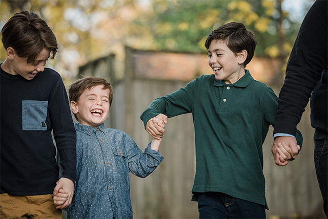 a professional photo of siblings dressed in fall shades of denim, green and brown, one of the best family photo outfit ideas