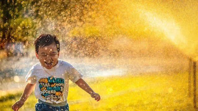 Happy Asian boy running through water