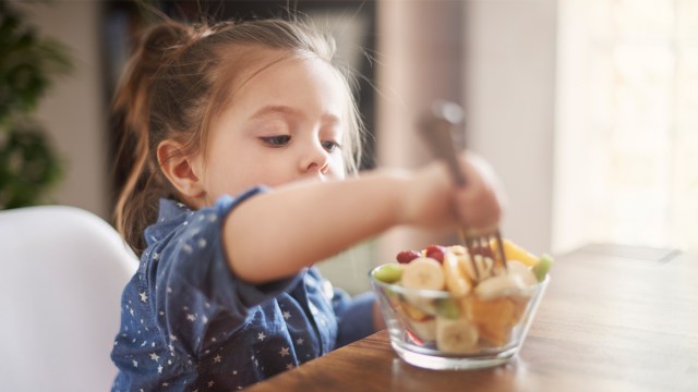 A little kid who is always hungry having some fruit salad