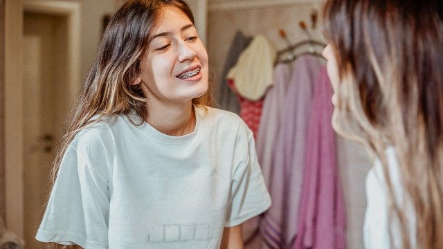 teen girl looking at her skin in the mirror