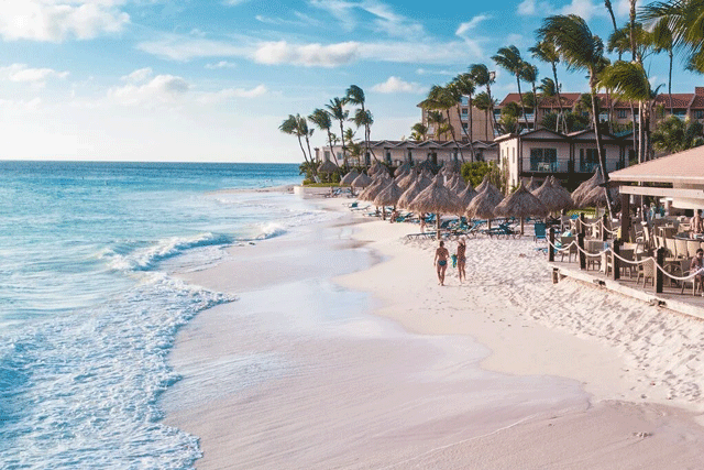 People walking on the beach in front of Diva Aruba all-inclusive for families