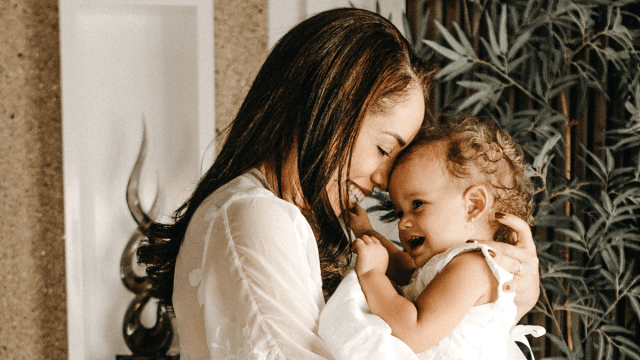 a mother snuggling her baby with pierced ears for a story on what to know about infant ear piercing